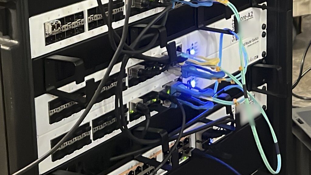 Rack mit beschrifteten MikroTik-Switches, Kupfer- und Glasfaser-Patchkabeln